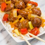 Sweet and Sour Meatballs on a white serving plate on top of white rice.