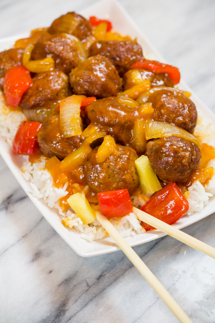 Sweet and Sour Meatballs on a white serving plate on top of white rice.