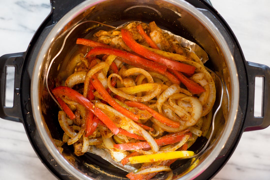 Top view of an instant pot filed with fajita chicken, onions, and bell peppers. 