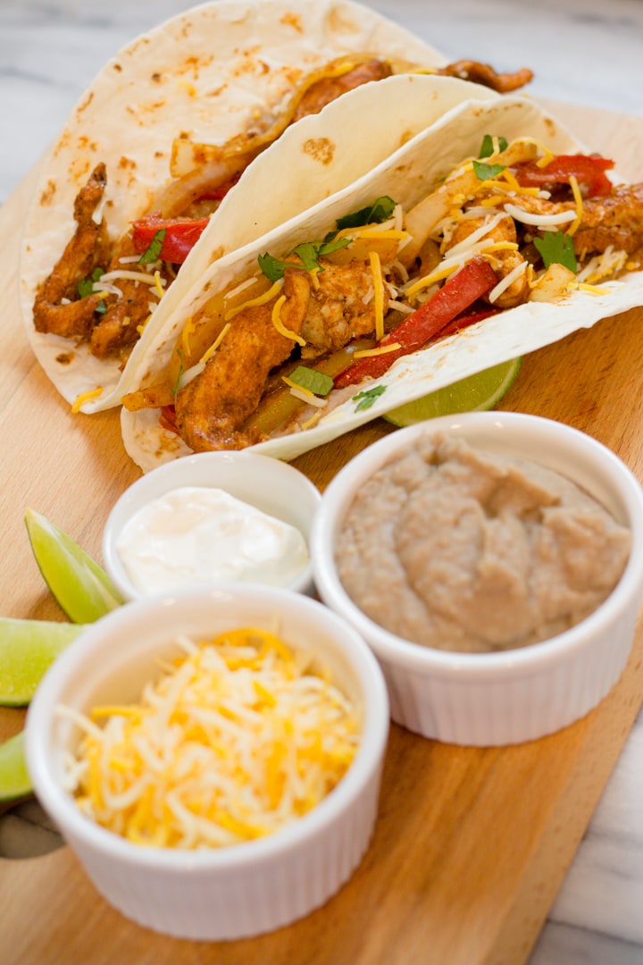 Hero image if chicken fajitas next to small bowls filled with toppings.