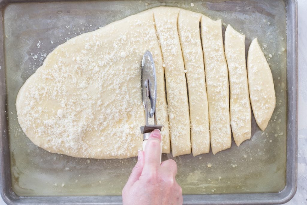 Breadsticks being cut on pan