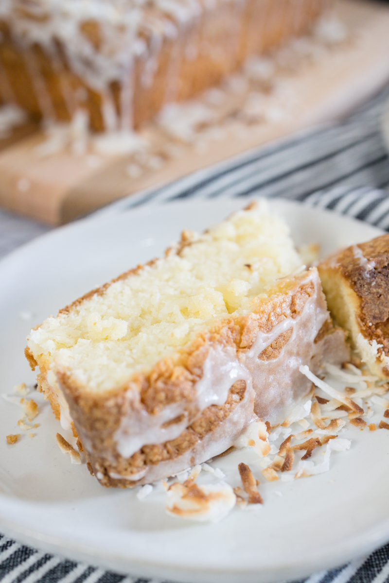 A slice of coconut pound cake on a white plate.