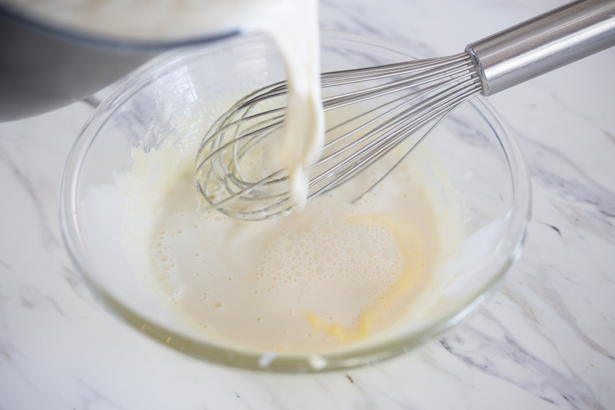 Temper eggs by adding headed cream to eggs slowly and whisk