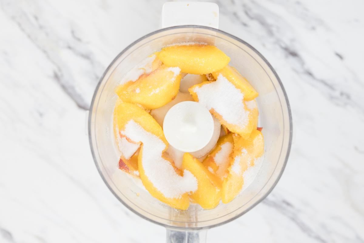 sliced peaches with sugar in food processor