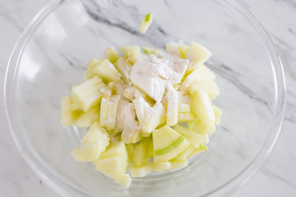Sliced apples in bowl with flour