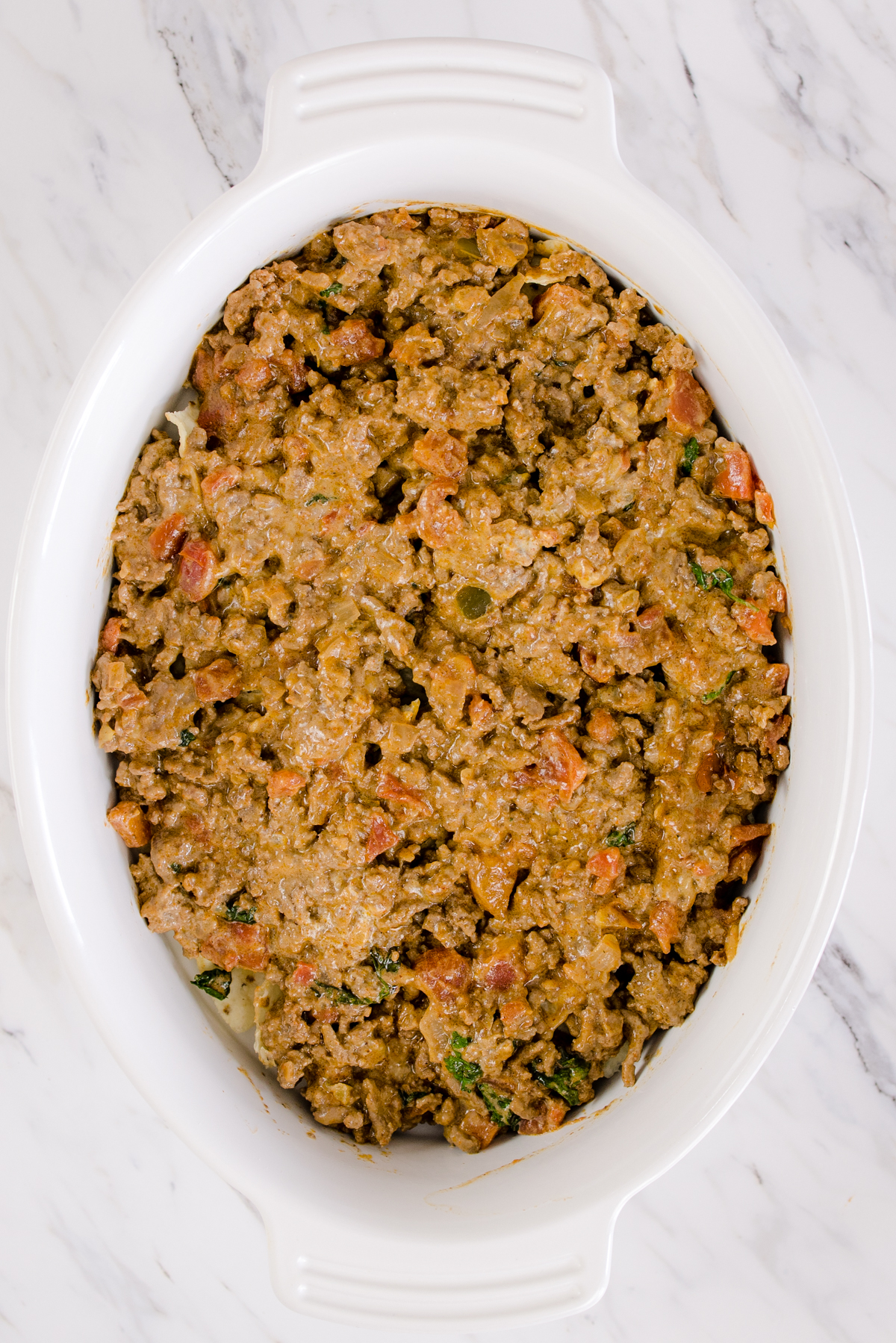 Top view of casserole dish with a layer of cooked ground beef on top. 