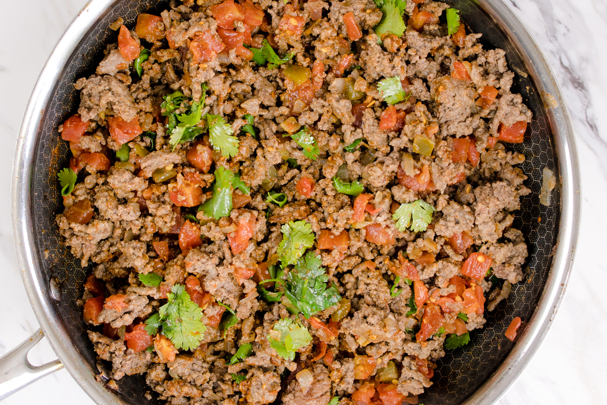 Top view of frying pan with a ground beef mixture in it with vegetables mixed in. 