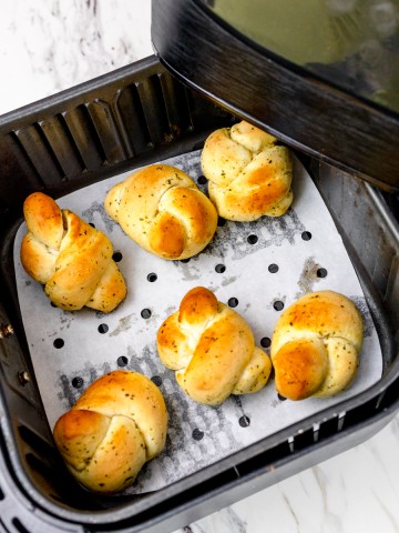 Top view of Garlic Knots on top of parchment paper in an air fryer tray.