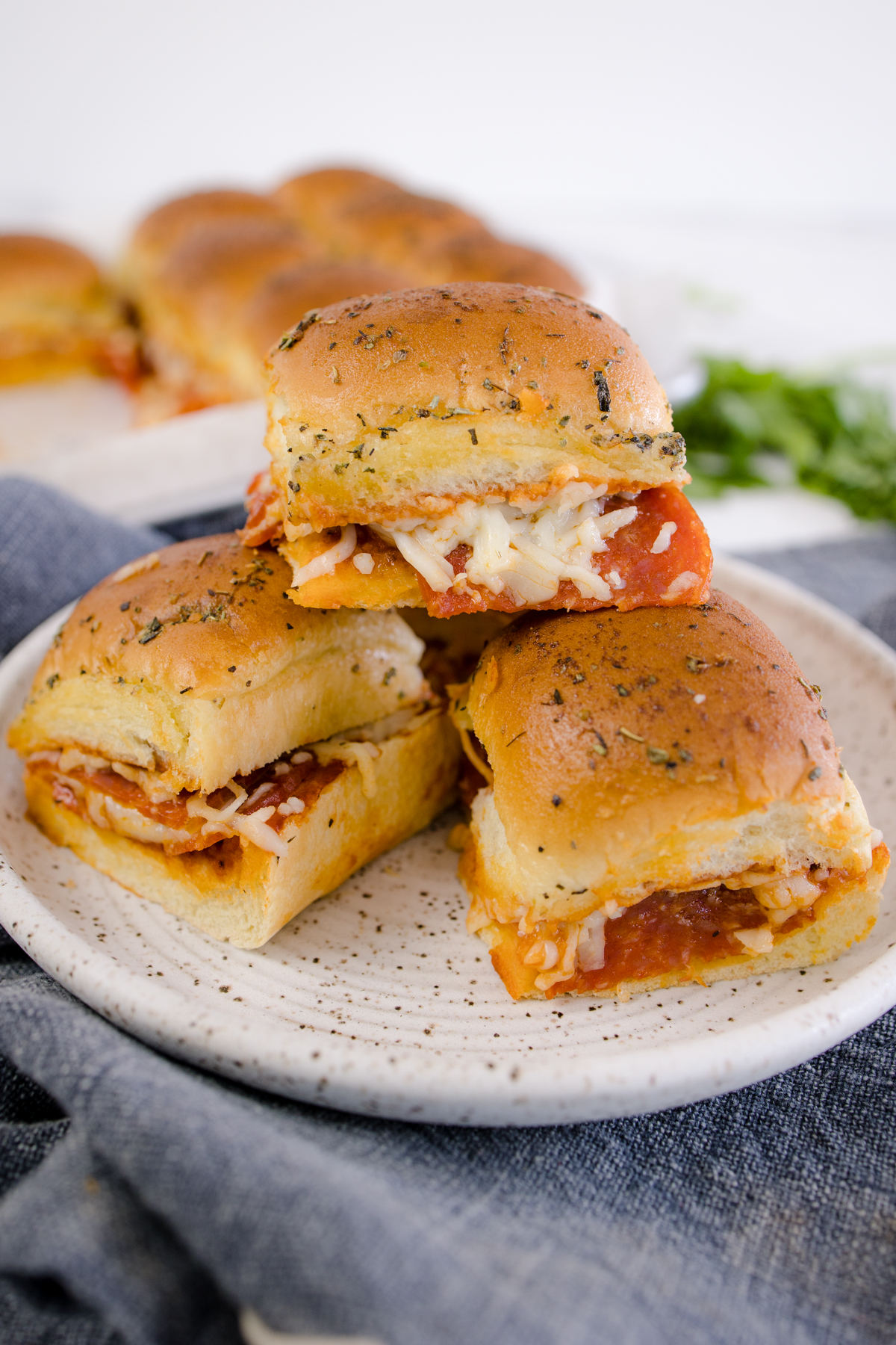 Three Pizza Sliders piled on a white plate. 