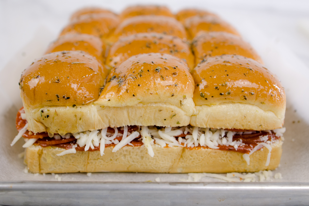 Close up side view of pizza sliders on a baking sheet.