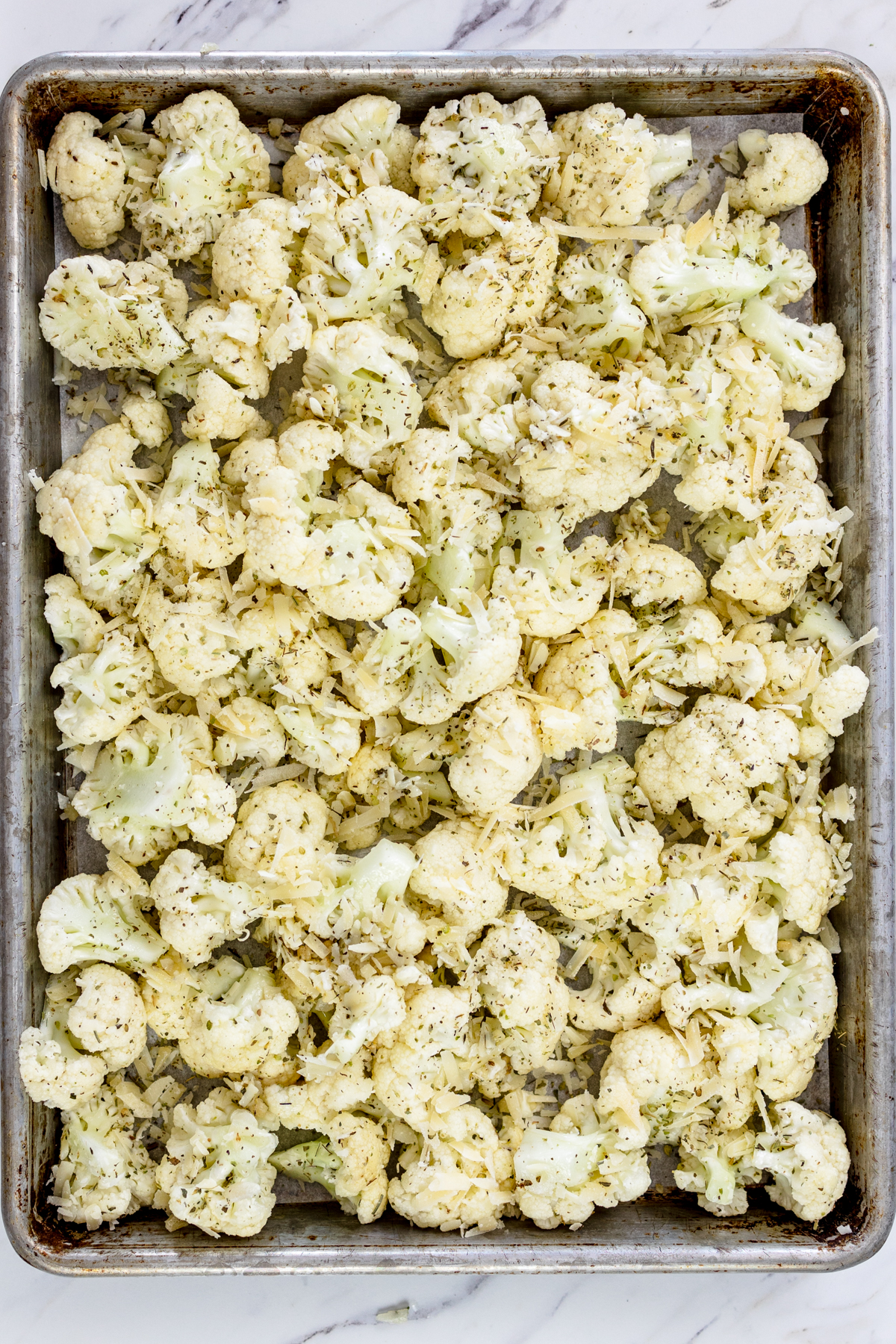 Top view of a baking tray with seasoned cauliflower on it. 