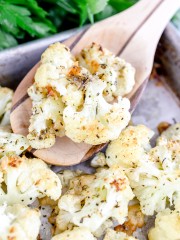 Close-up of Roasted Cauliflower with Parmesan cheese on a baking tray with a wooden spoon in it.