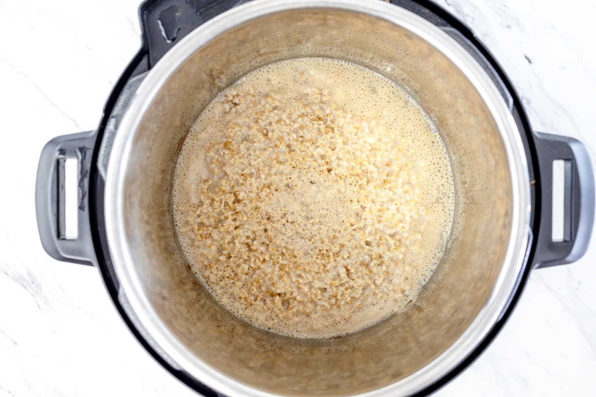 Top view of an instant pot with oats at the bottom with water in it. 