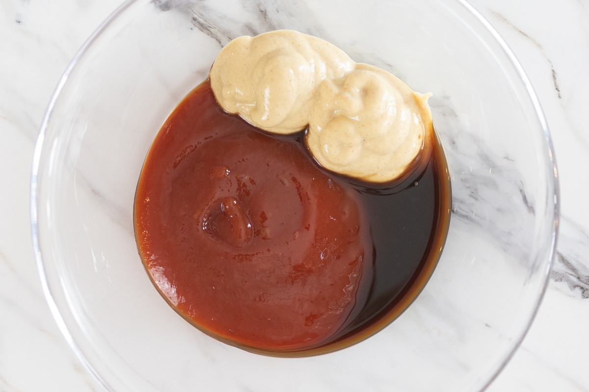 Top view of ketchup, BBQ sauce and mustard in a bowl, unmixed. 