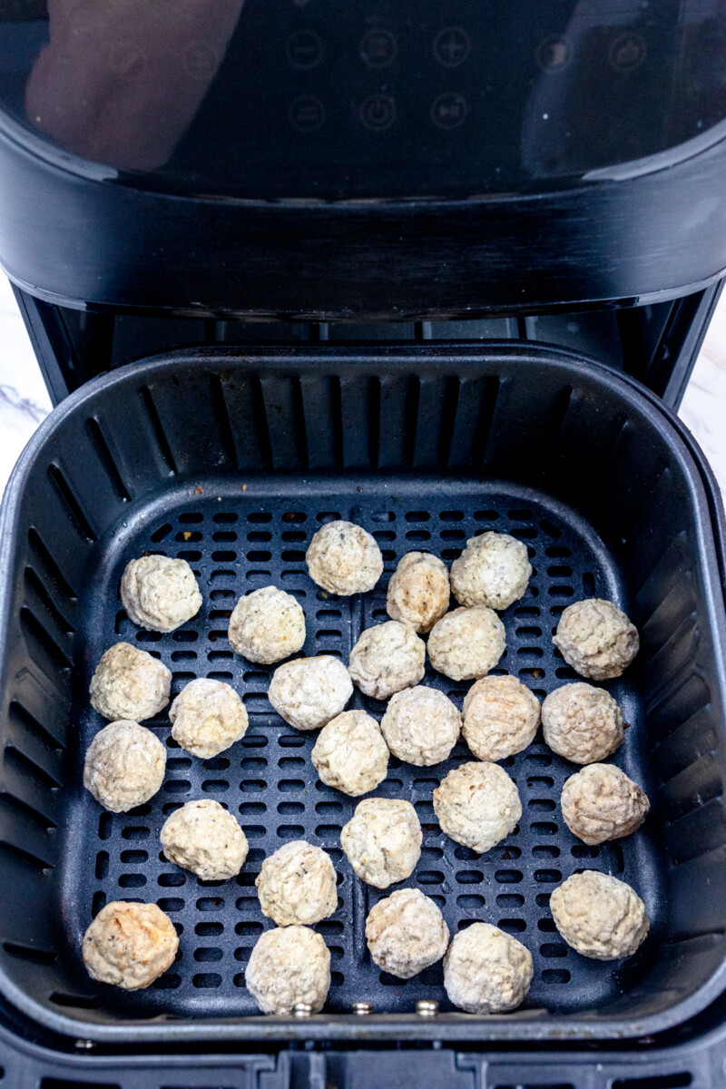 Top view of frozen meatballs in an air fryer.
