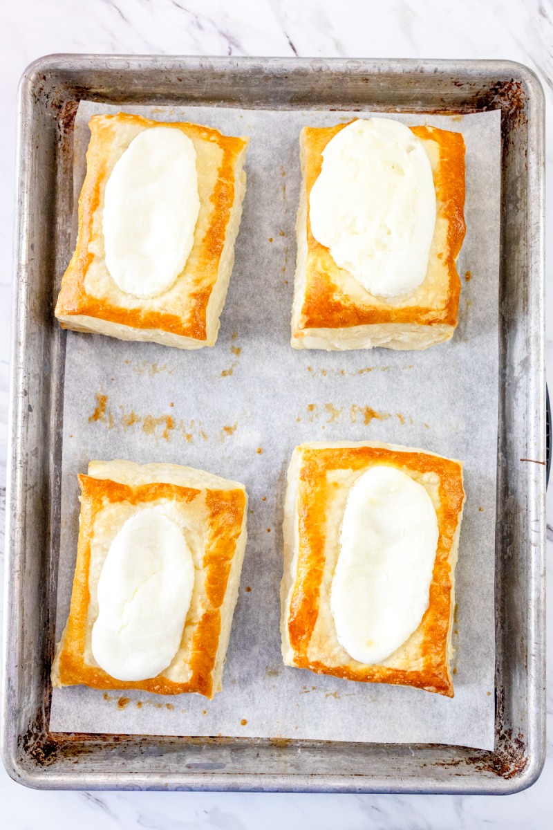 Top view of freshly baked puff pastry cream cheese danishes on a baking tray.