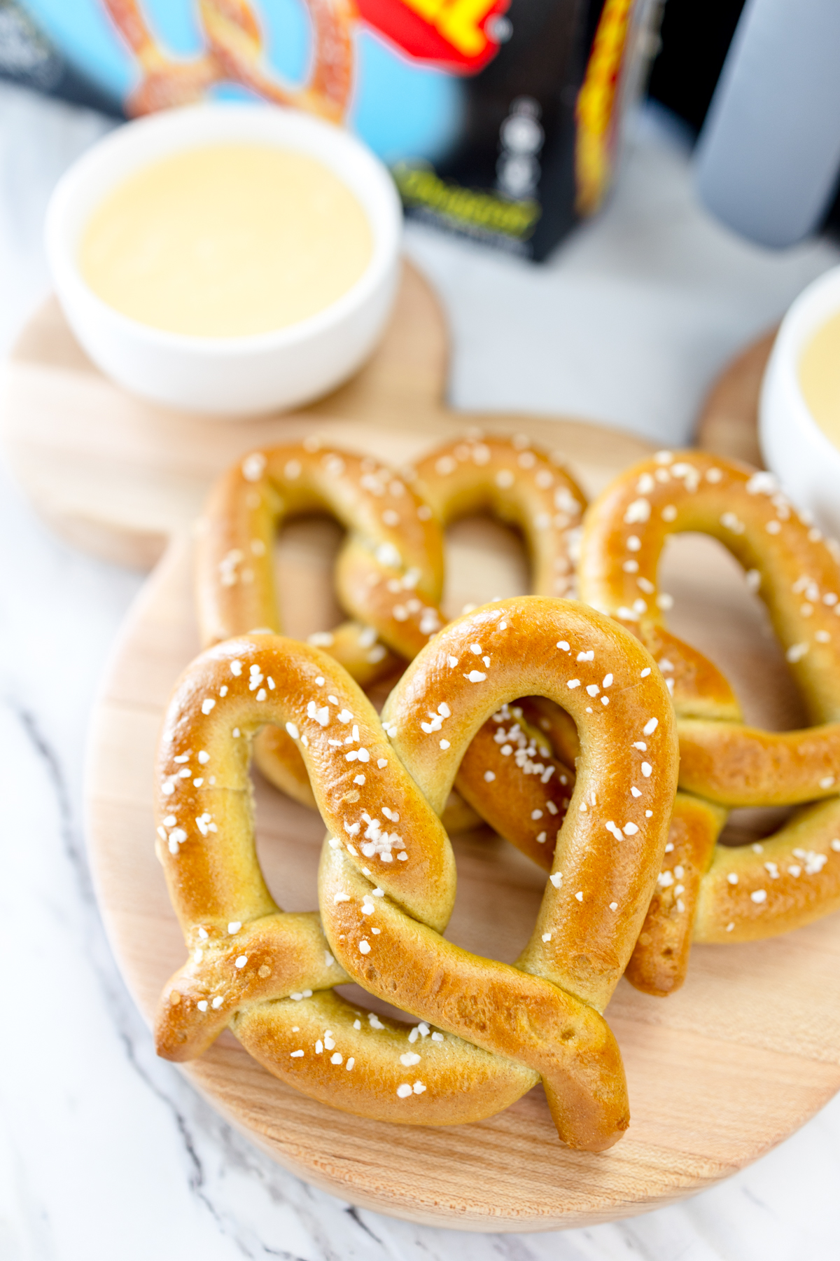 Air-fried pretzels on a serving board with a ramekin of sauce in the background.