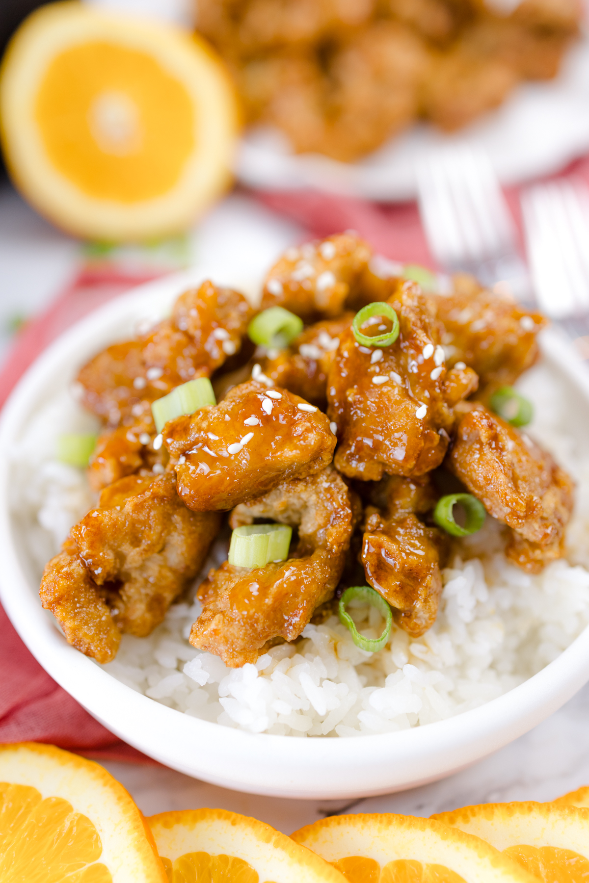 Close up of Orange Chicken on rice on a plate.