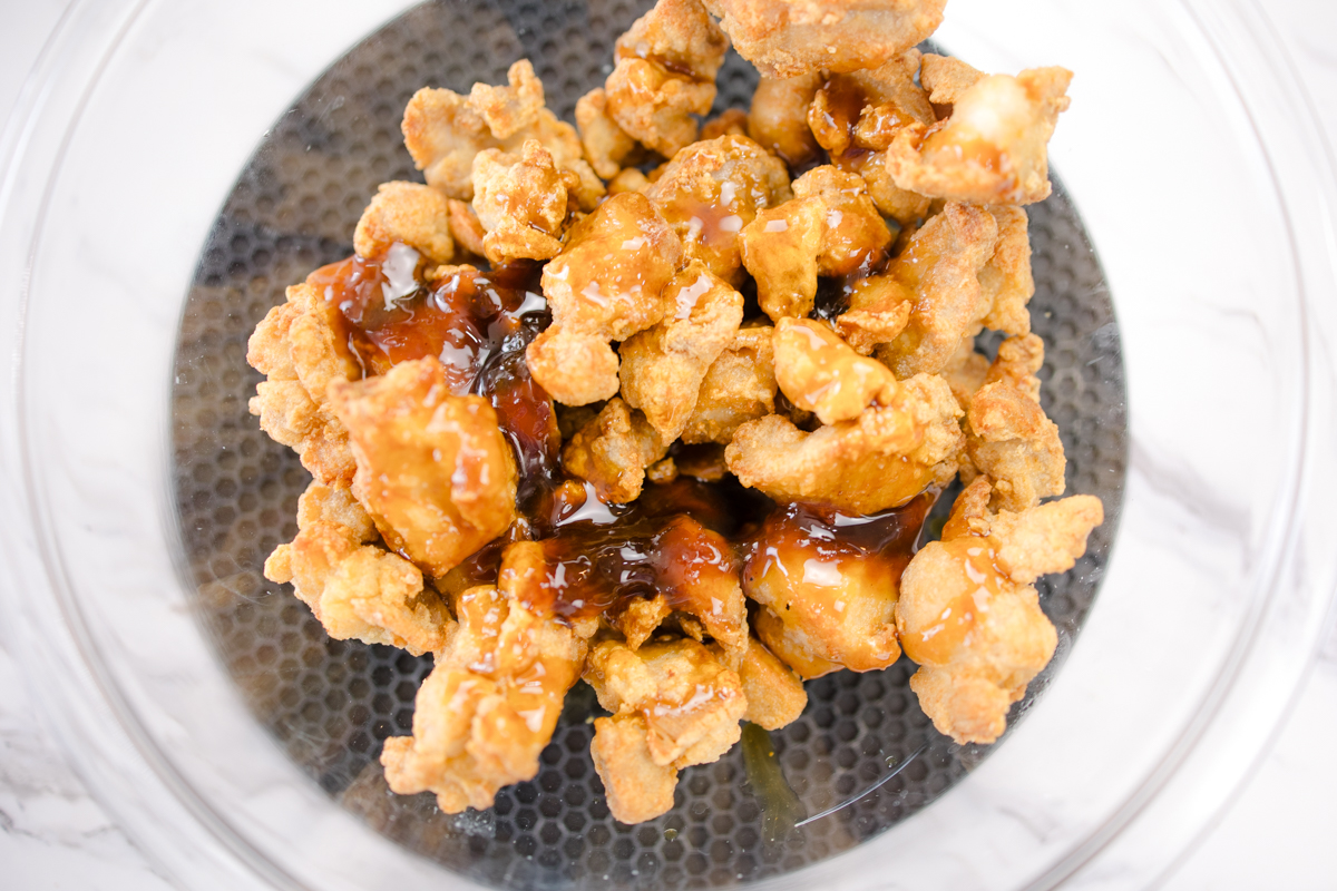 Top view of ORange chicken in sauce in a bow, about to be tossed.