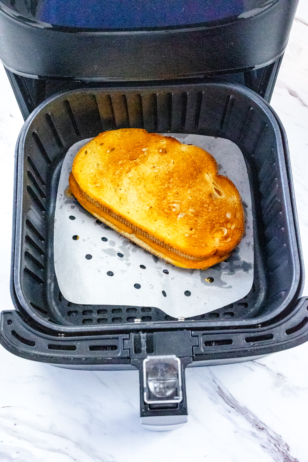 Top view of a cooked grilled cheese sandwich in the bottom of an air fryer.