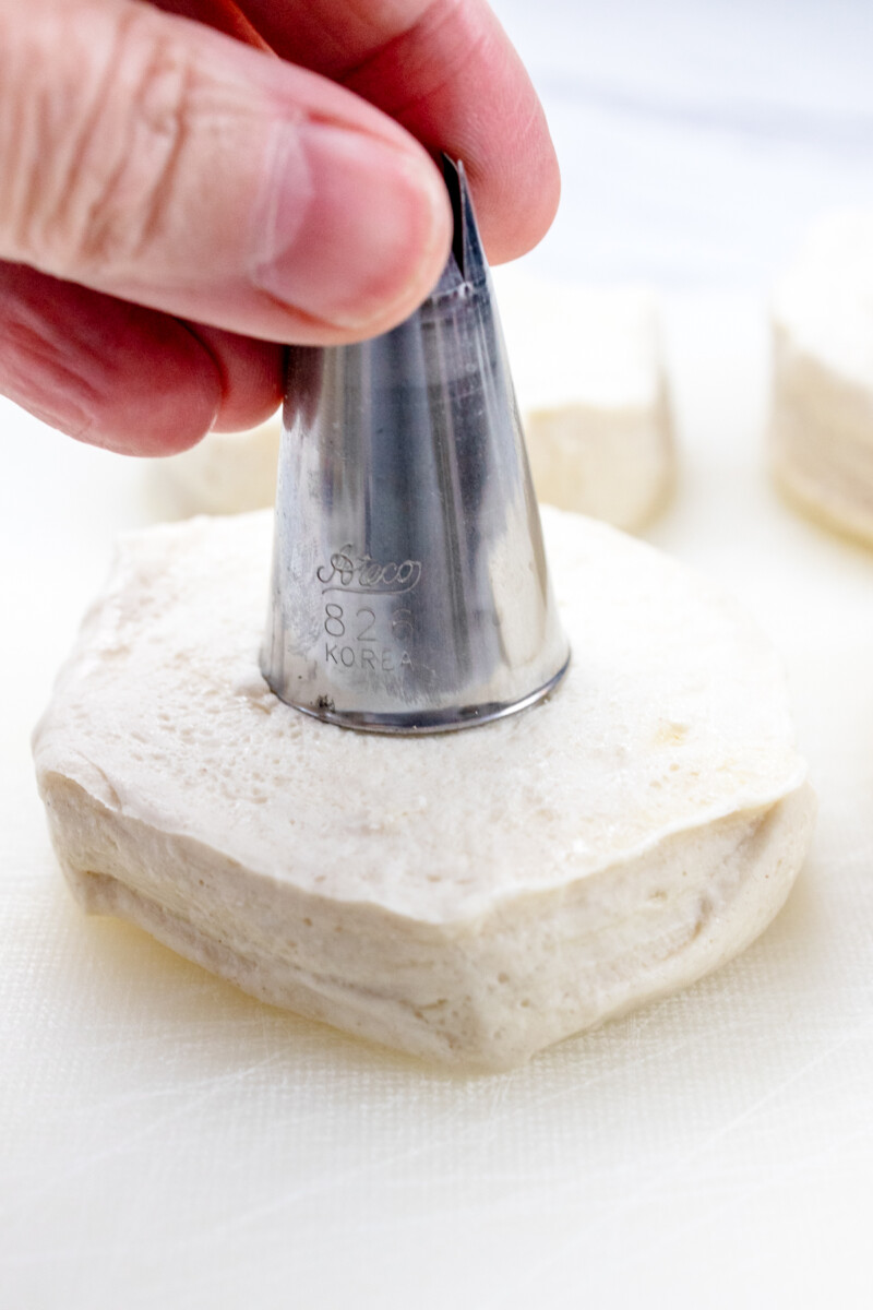Close view of uncooked biscuit with hole being cut from it.