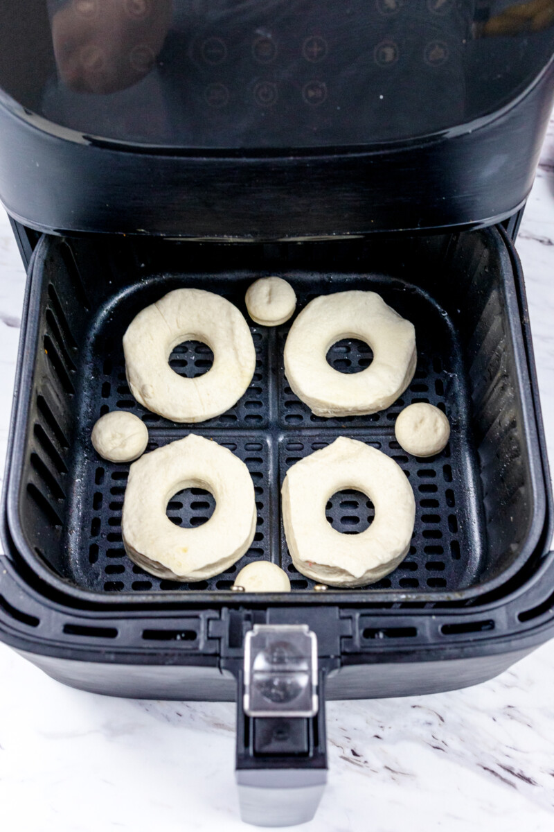 Top view of an air fryer basket with uncooked biscuits in it.