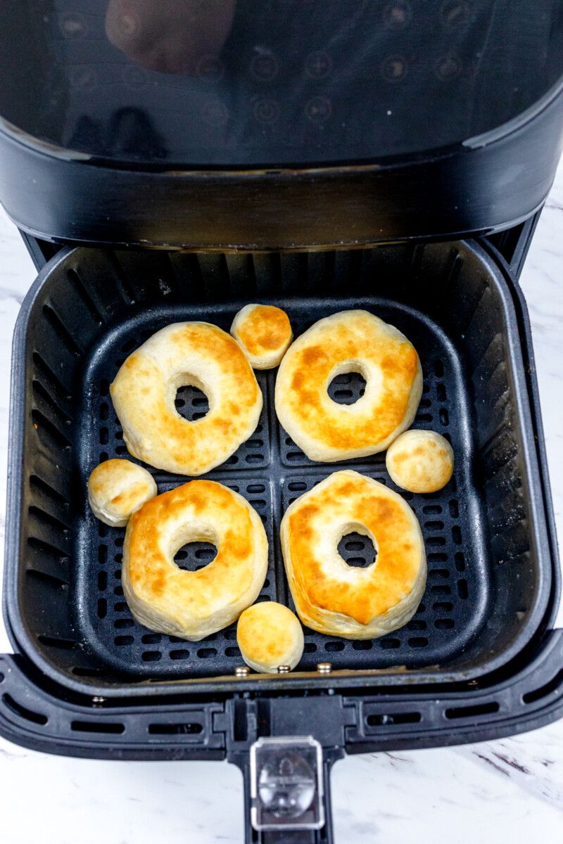 Top view of an air fryer basket with cooked biscuits in it.