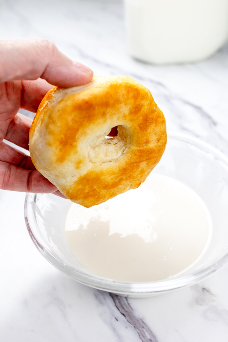 Close up view of a biscuit donut about to be dipped in icing.