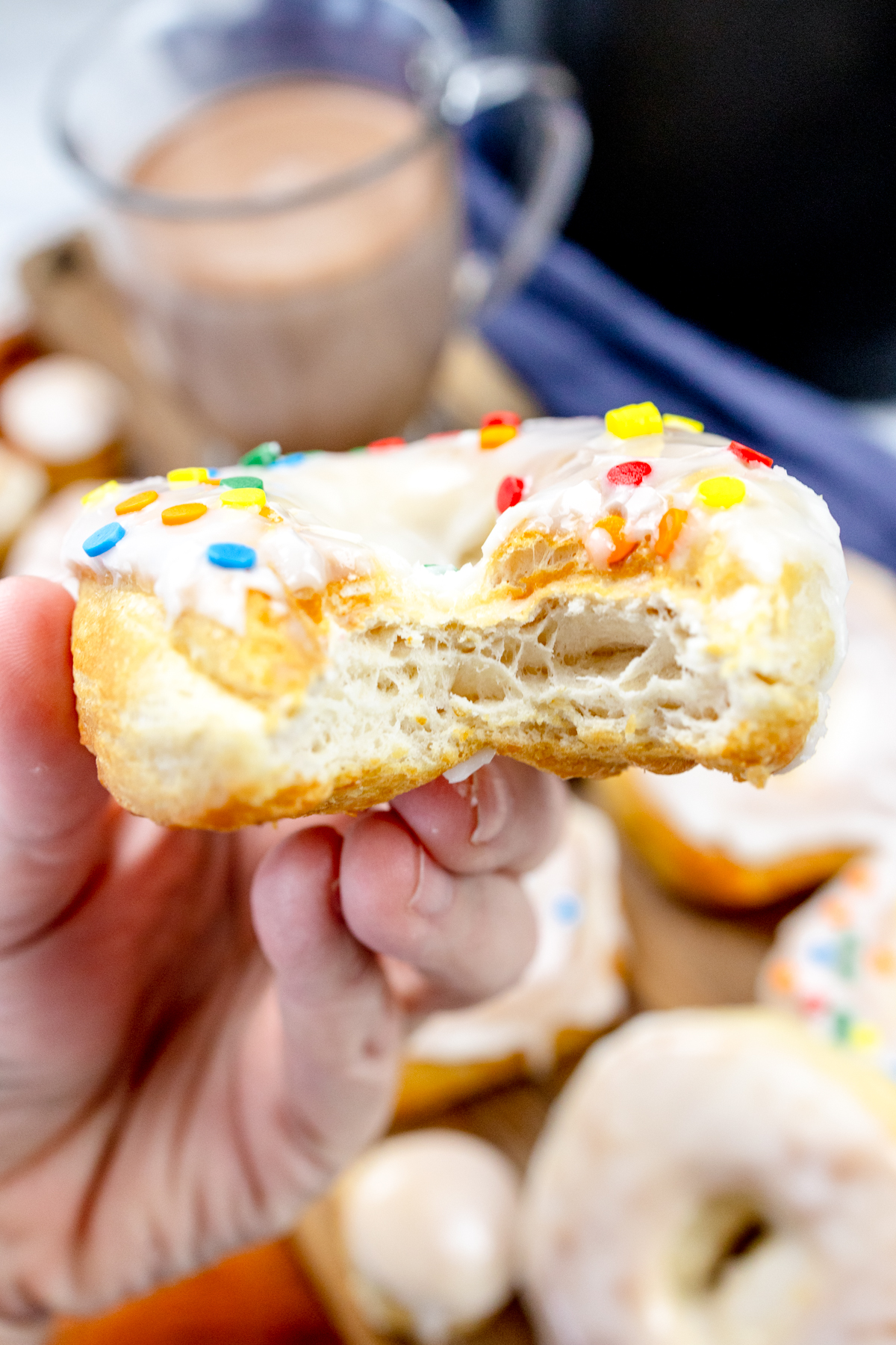 Close view of an iced and decorated biscuit donut with a bite taken from it to reveal the inside.