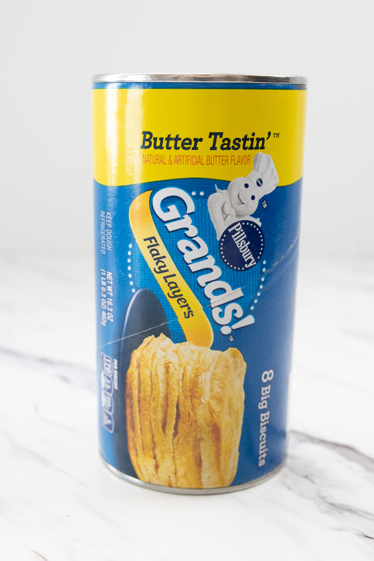 Close up view of a can of Pillsbury Grand Biscuits on a white marble surface.