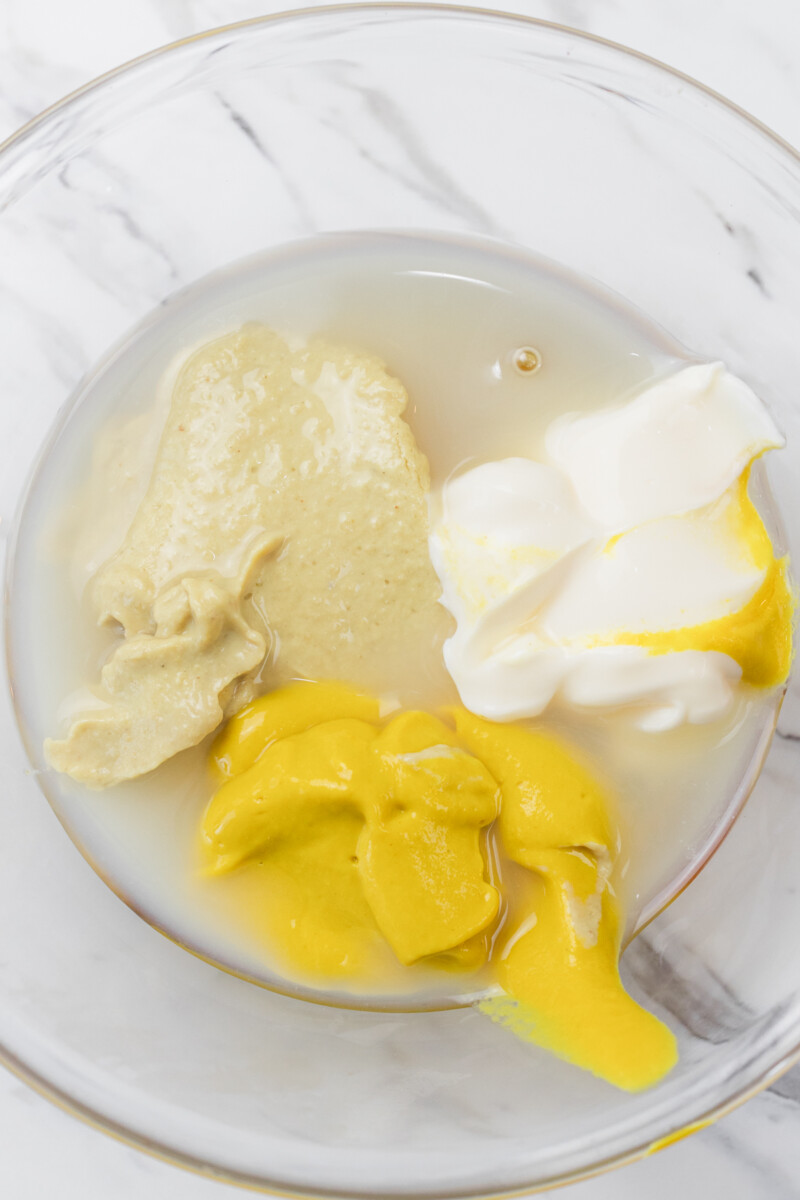 Top view of a glass mixing bowl with ingredients for honey mustard dipping sauce in it.