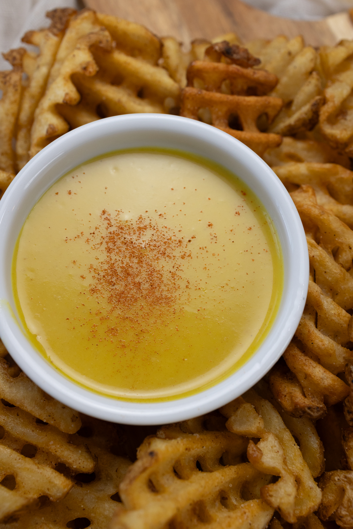 Top view of honey mustard dipping sauce in a small ramekin surrounded by waffle fries.