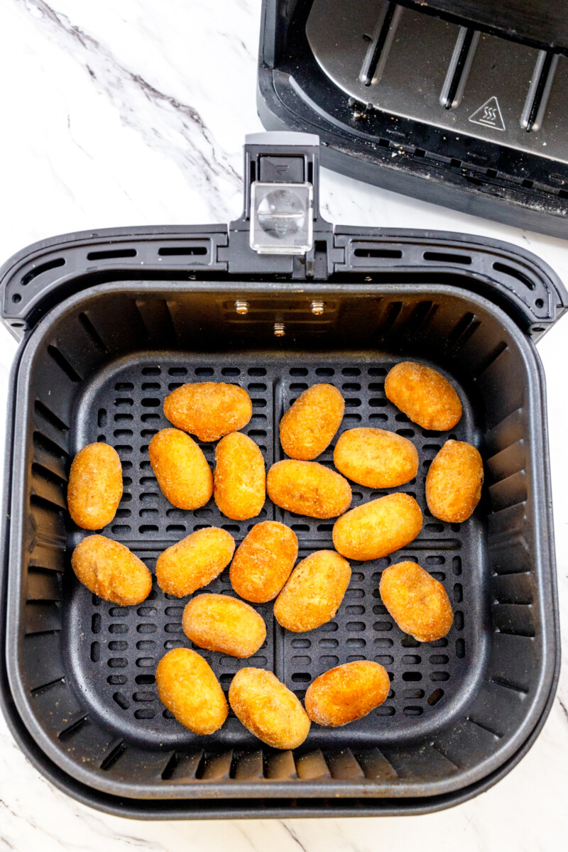 Top view of cooked mini corn dogs in an air fryer basket.