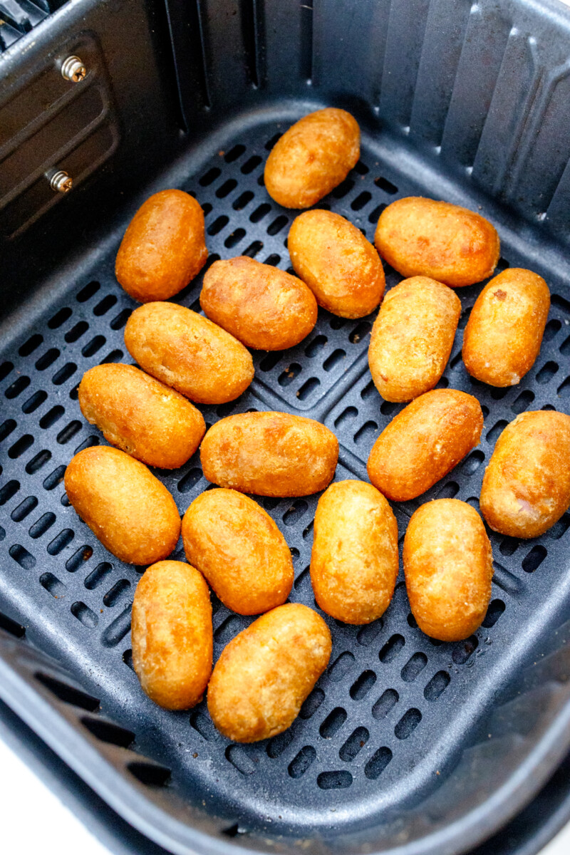 Top view of cooked mini corn dogs in an air fryer basket.