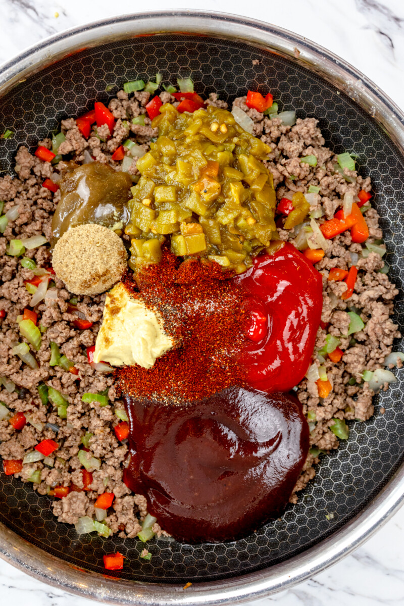 Top view of pan with ground beef mixture in it and sauces and seasonings added on top, ready to be mixed in.
