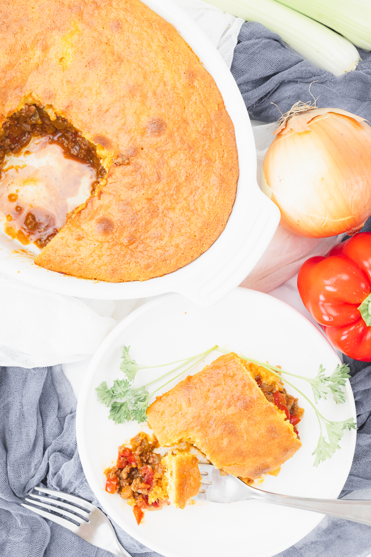 Top view of sloppy joe casserole on a table with a white plate next to it that has more sloppy joe casserole on it.