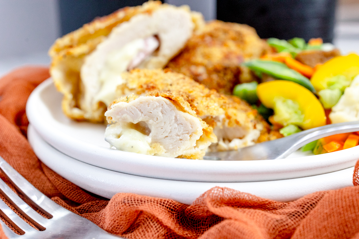 Side view of Air Fried Chicken Cordon Bleu on a white plate.