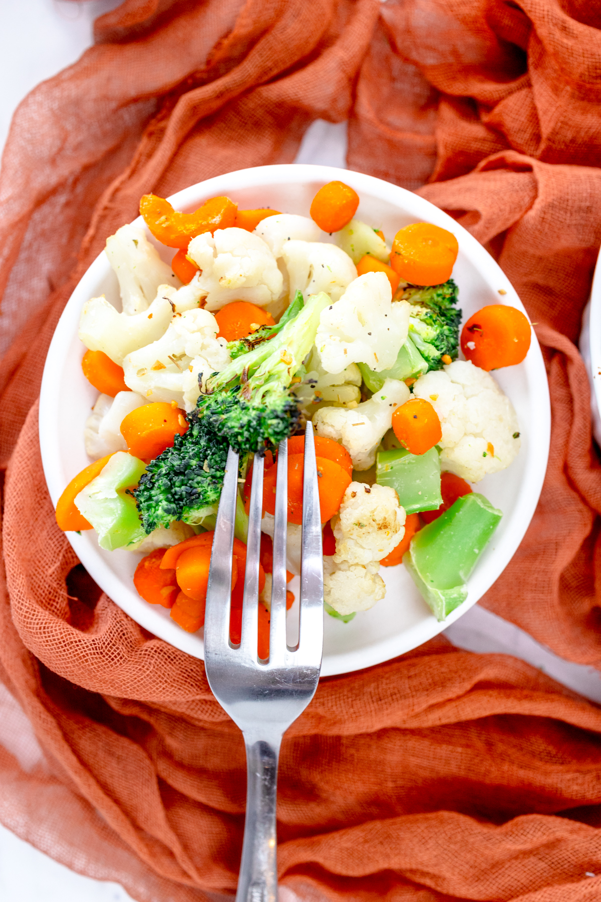 Top view of a white plate full of mixed vegetables.
