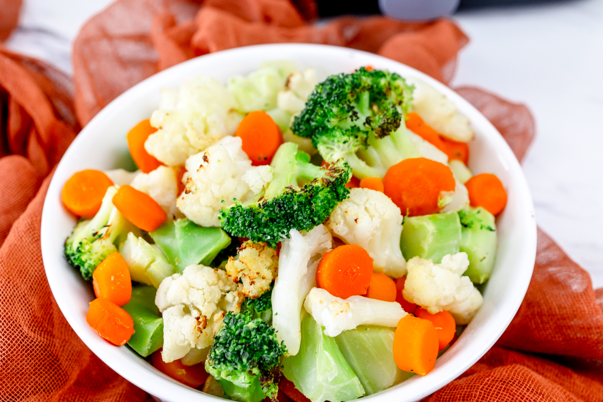 Close up view of a white bowl full of mixed vegetables.