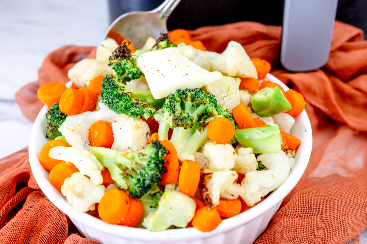 Close up view of a white bowl full of mixed vegetables.