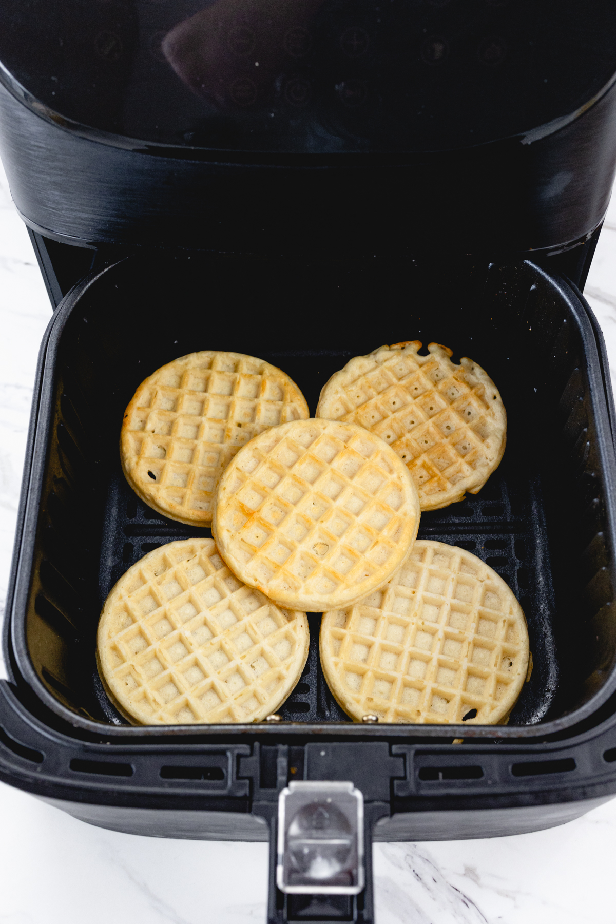 Top view of eggo waffles in an air fryer basket.