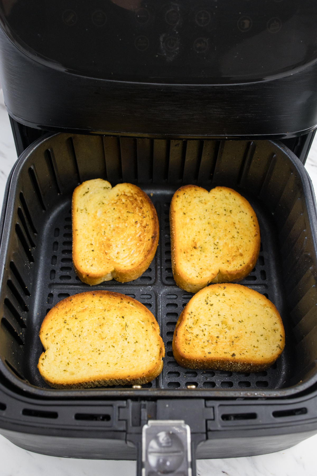 Top view of an Air Fryer basket with 4 slices of cooked Texas Toast in it.