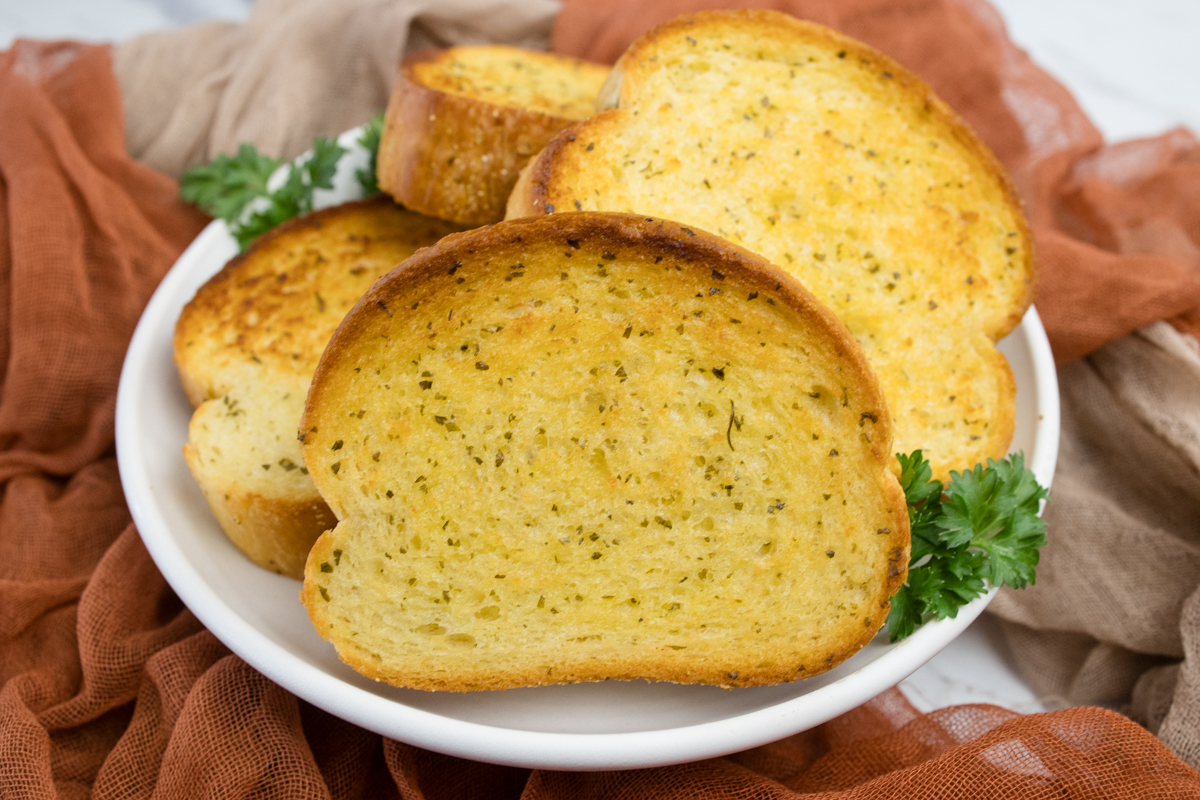 Close up view of Texas Toast stacked on a white plate.