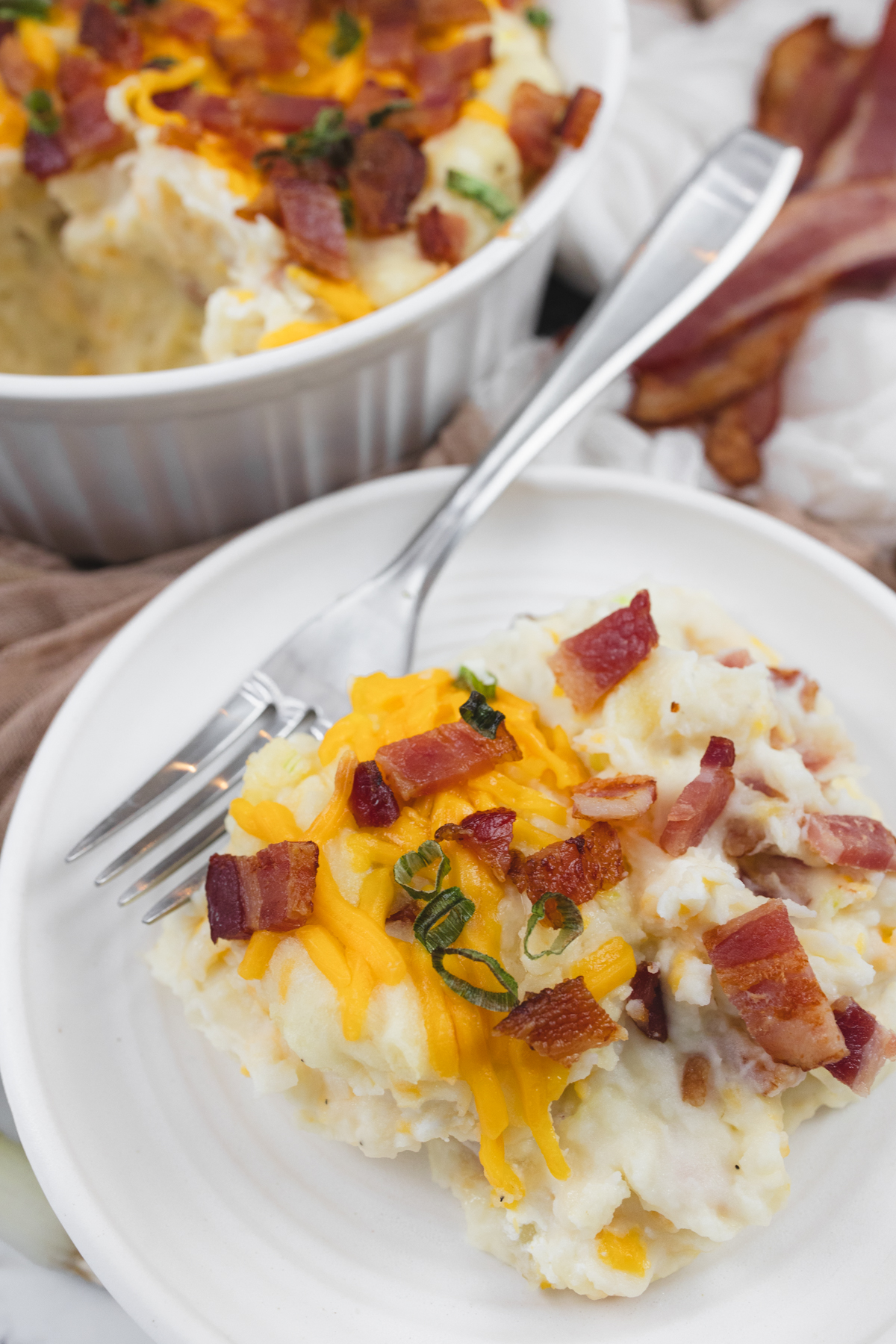 Close up view of a plate with a serving of loaded mashed potatoes on it.