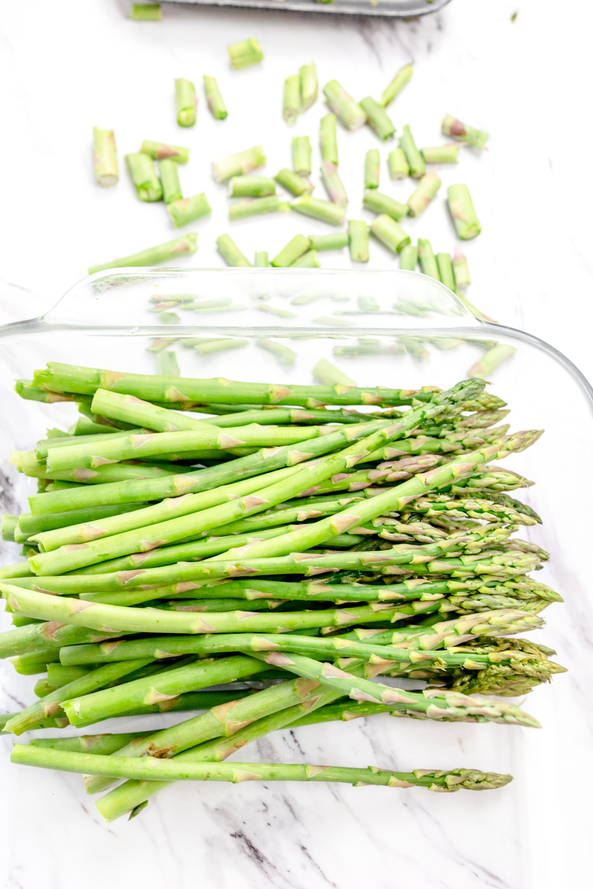 A top view of asparagus in a glass dish with the ends cut off.