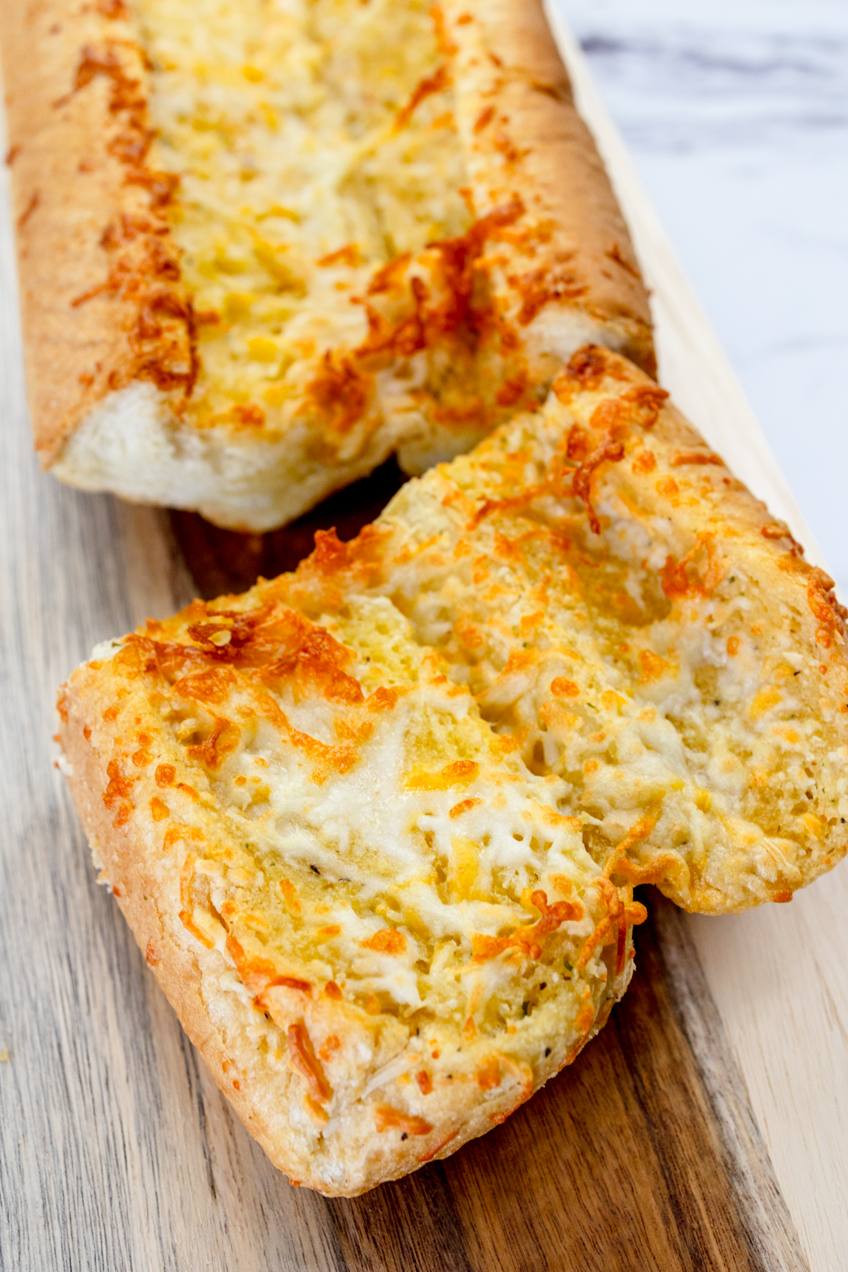 Close up image of air fried garlic bread on a wooden chopping board.