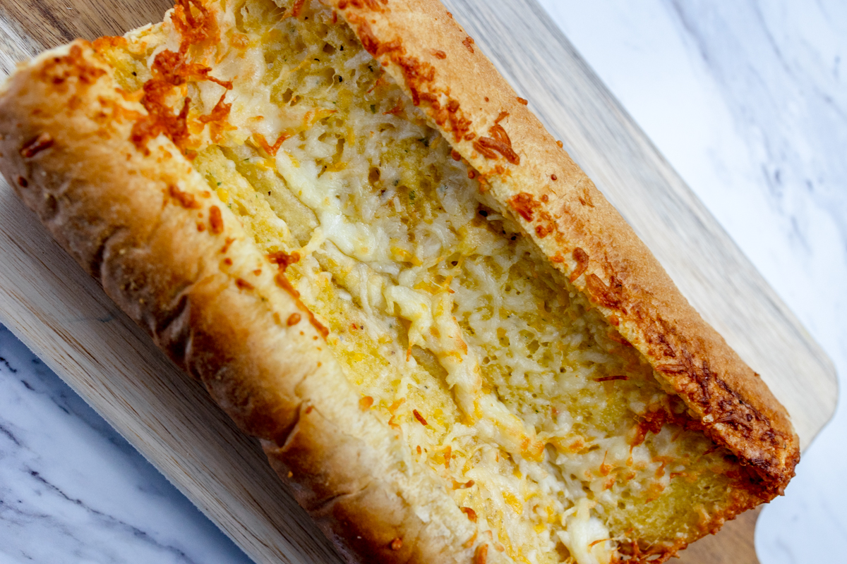 Close up image of air fried garlic bread on a wooden chopping board.