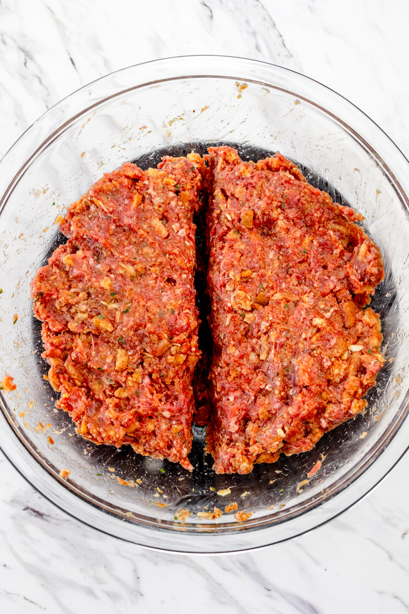 Top view of meatloaf mixture in large mixing bowl; the mixture is divided in half.