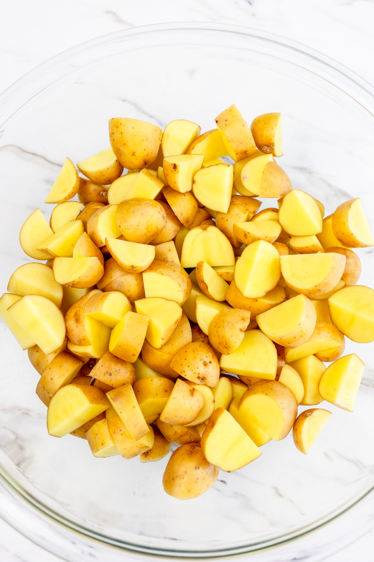 Potatoes tossed with Olive Oil in a large mixing bowl.