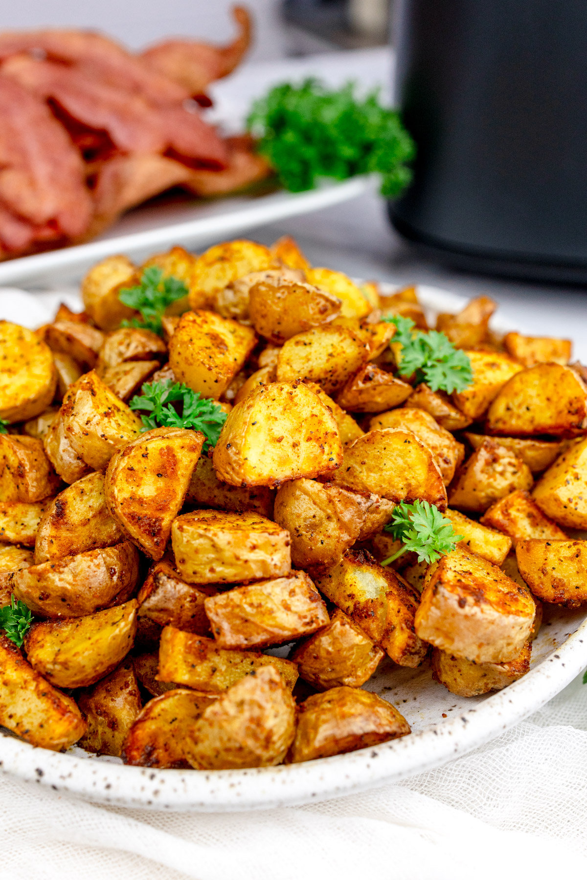 Air Fryer Breakfast Potatoes on a white plate with a leafy green garnish.
